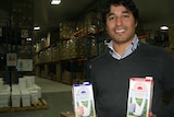 Man in warehouse holding cartons of macadamia milk