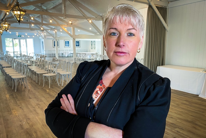 Mary-Anne Lowe stands in front of rows of chairs at her reception venue