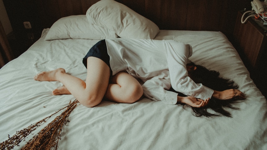 A woman lays on a bed fully clothed.