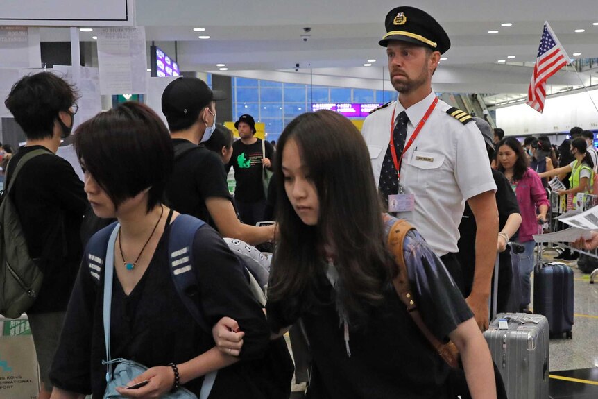 Passengers and flight crew file into Hong Kong International Airport as protesters hand out flyers