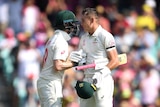 Two Australian cricketers share a handshake to celebrate a century.