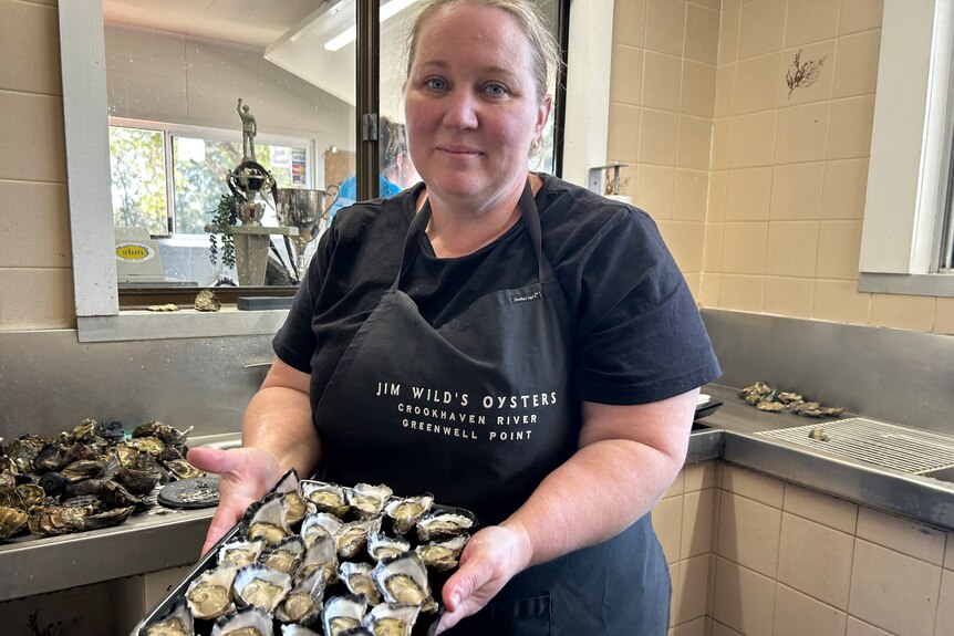 A woman holding a tray of oysters.