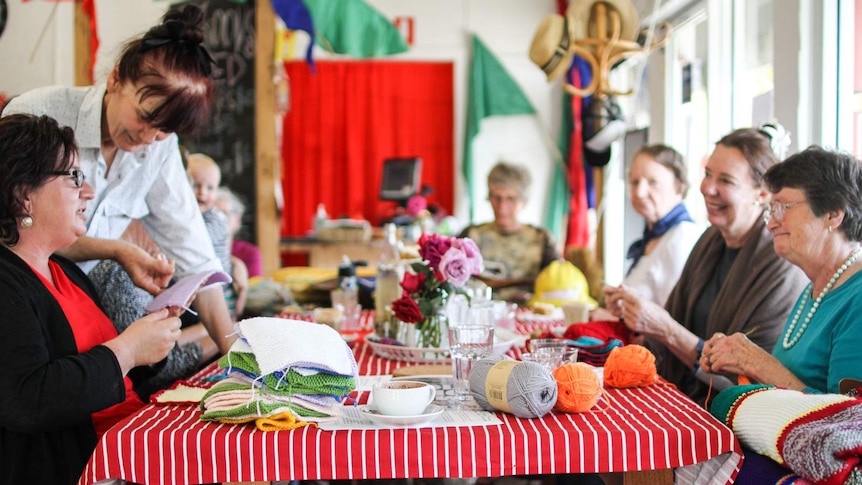 A group of local women from Taradale sit at a table knitting for victims of family violence.