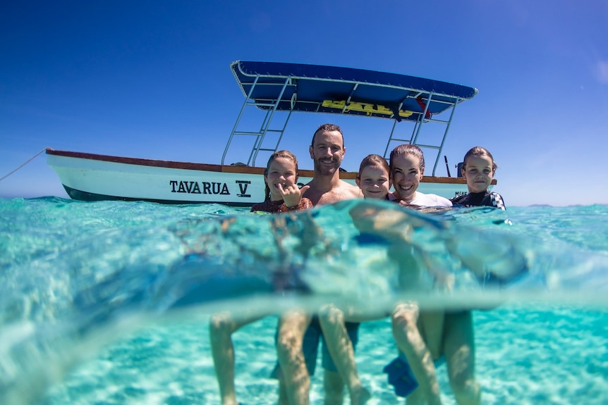The Cardone family smile while standing in blue water while on holiday in Fiji.