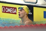 A swimmer in the water next to the lane rope looks up at the scoreboard after a race at the world titles.