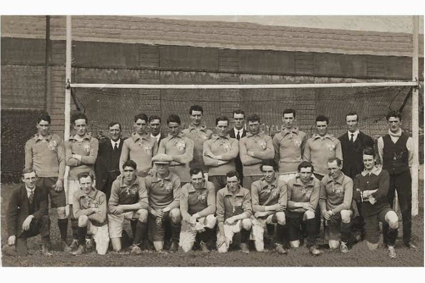 A sepia-tinted black and white photo of a group of men posing in front of some goal posts