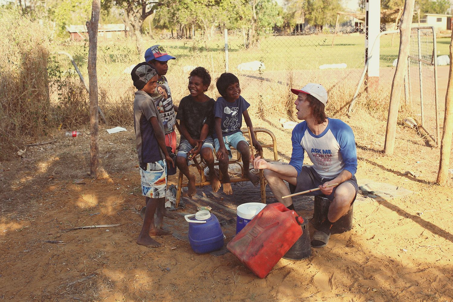 A group of kids watch on as a man hits objects with drum sticks.