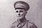 An early photograph of a WW1 soldier in uniform, standing with his hands behind his back