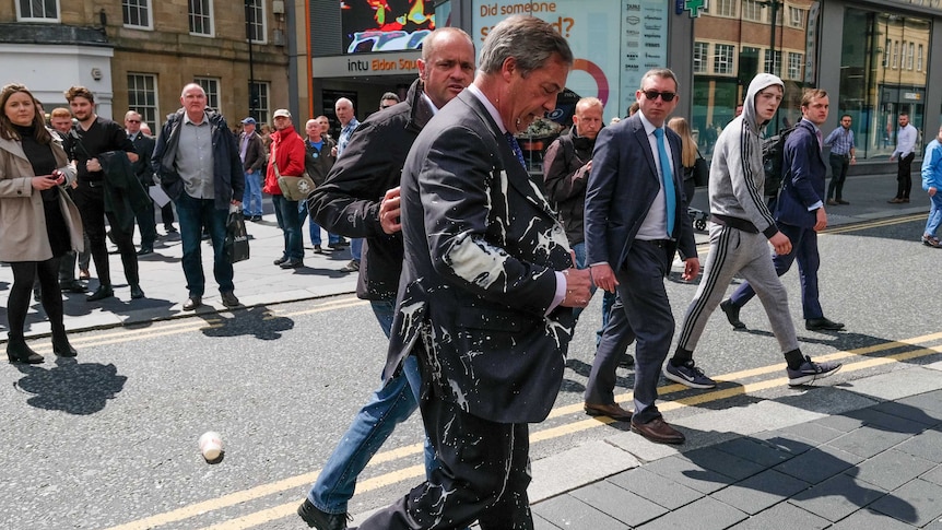 Nigel Farage walks away after a milkshake was thrown over him.