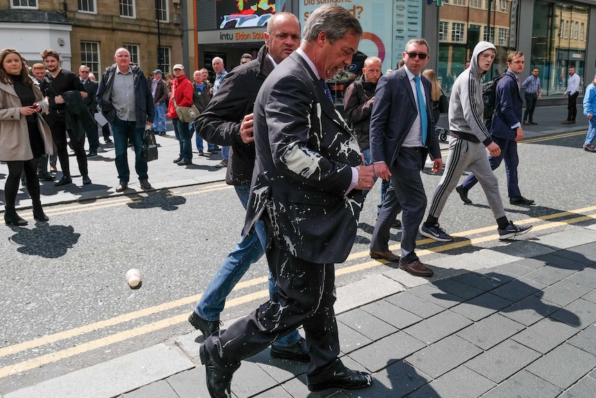 Nigel Farage walks away after a milkshake was thrown over him.