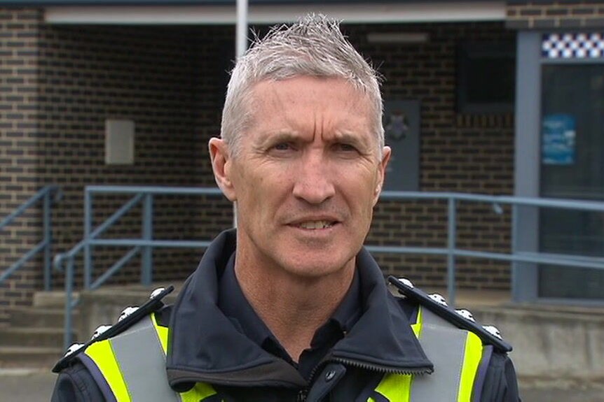 Inspector Shane Cashman, a policeman with white hair, speaks outside a police station.