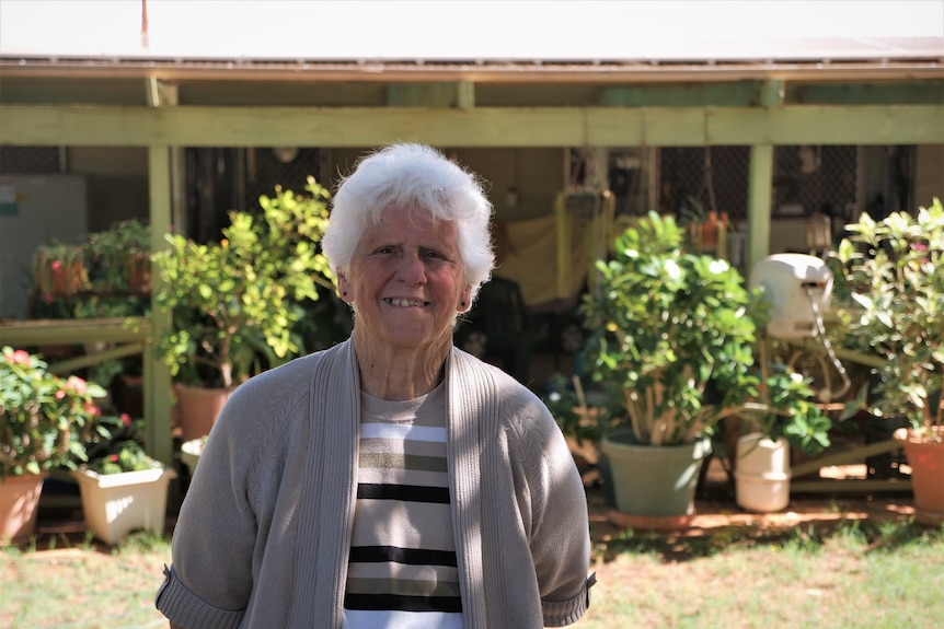 Grey haired lady standing in front of her house.