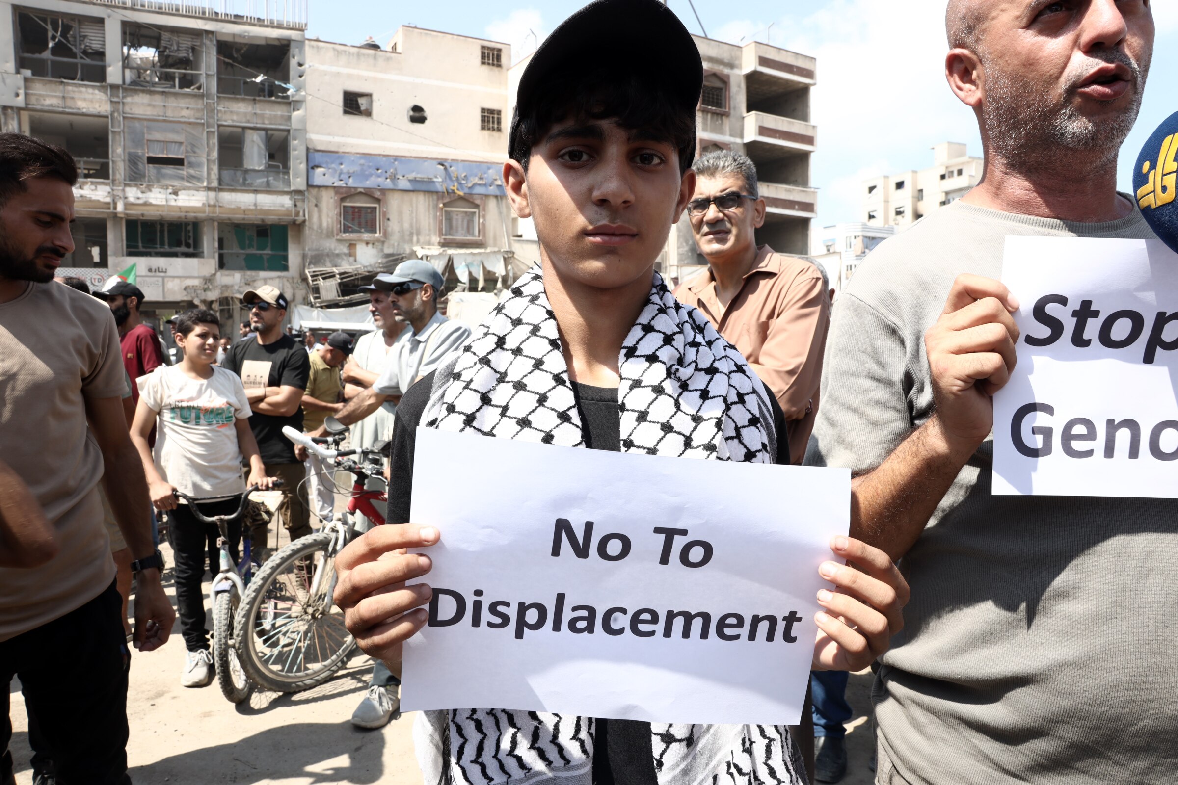 A young boy holding a sign saying 'No to Displacement'