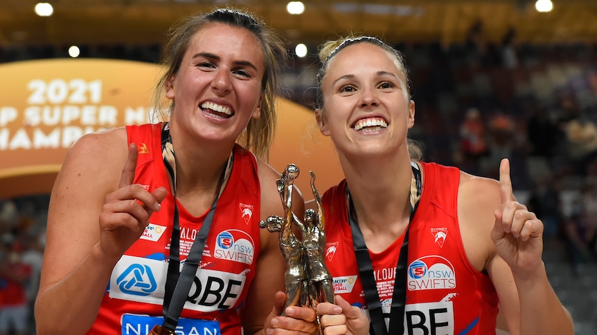 Two NSW Swifts Super Netball players pose with a trophy after the grand final.