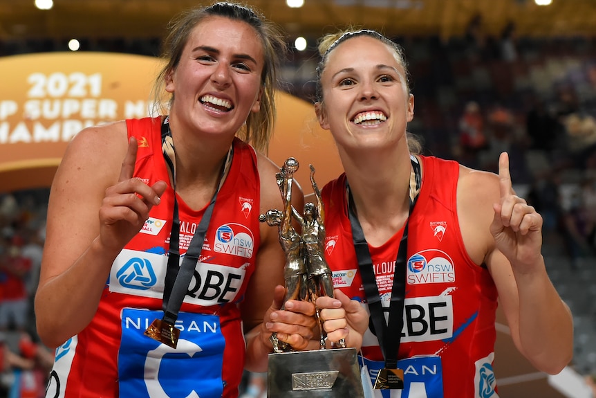 Two NSW Swifts Super Netball players pose with a trophy after the grand final.