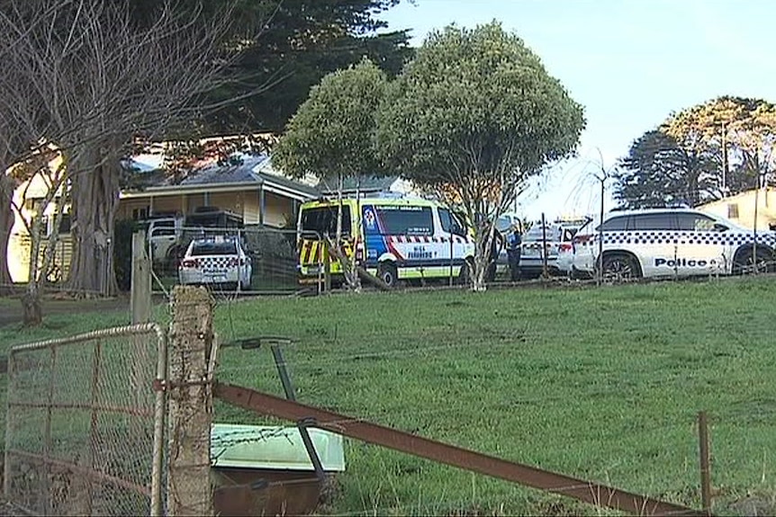Police cars and an ambulance on a rural property.