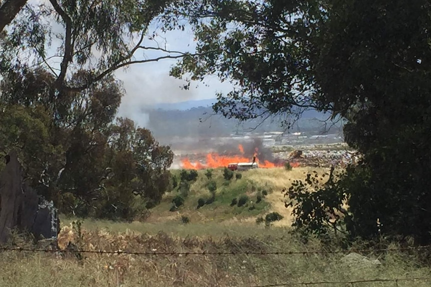 A large fire in an industrial area seen from a distance.