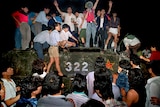 A group of chinese people climb on a tank and look angry.