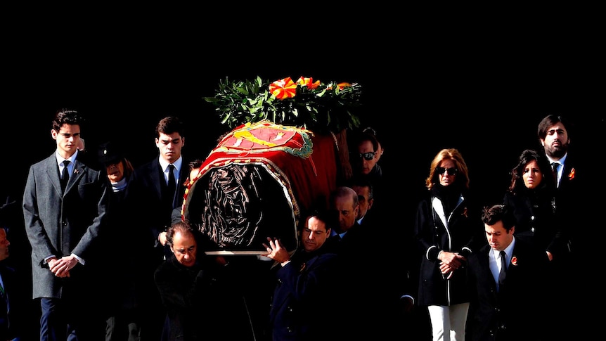 Franco's coffin is carried down steps by eight men and surrounded by several family members