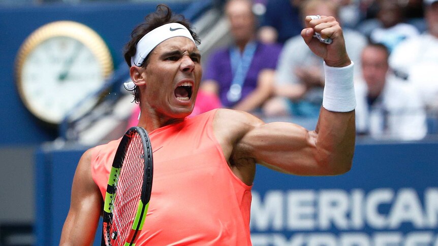 A male tennis player clenches his fist and screams in joy while leaning back