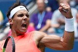 A male tennis player clenches his fist and screams in joy while leaning back