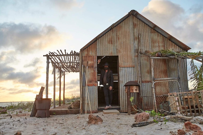 Warwick Thornton stands in the doorway of his beach shack in The Beach documentary.