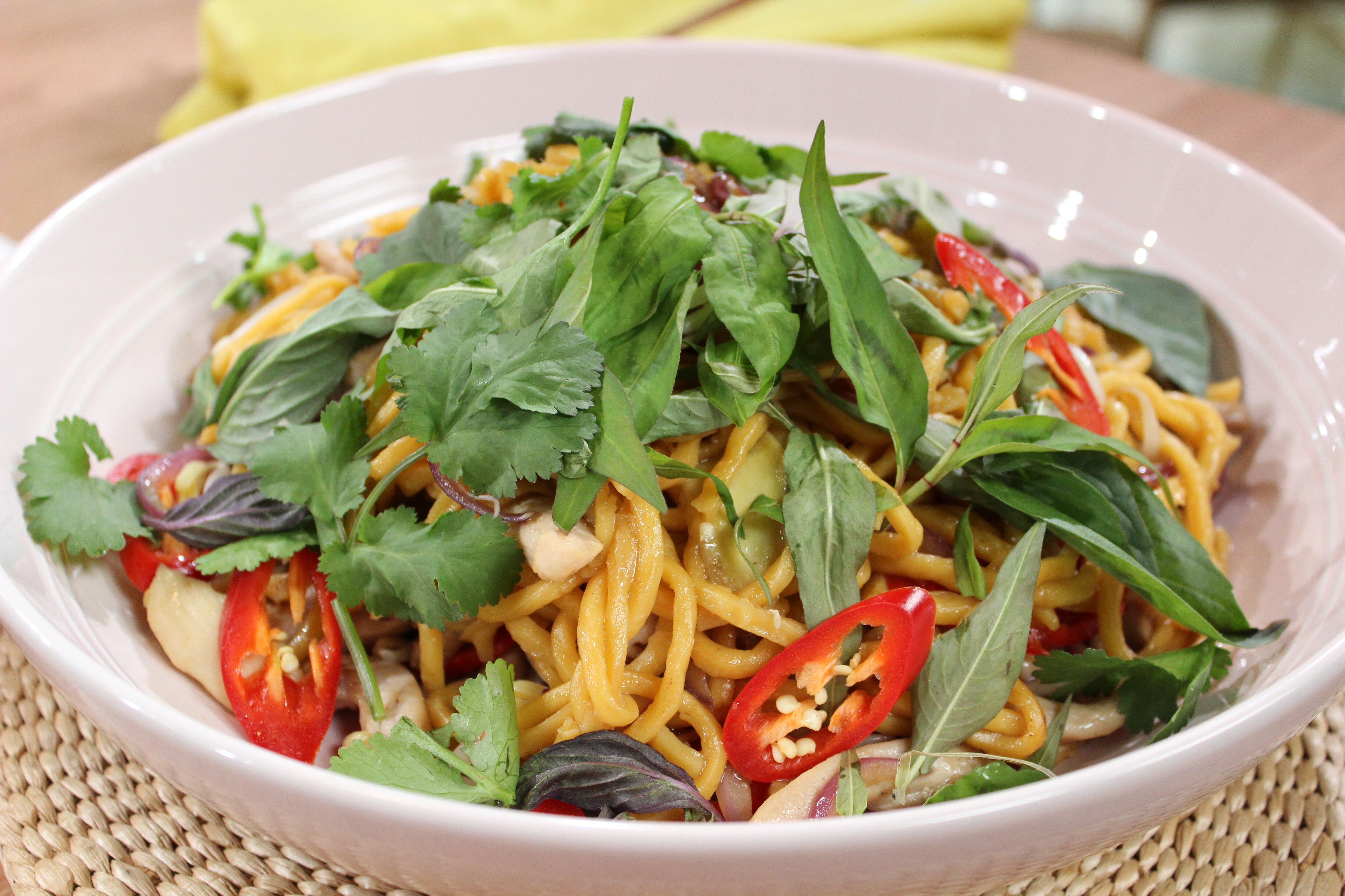 고추와 허브로 장식된 그릇에 담긴 완성된 호키엔 국수 볶음 사진