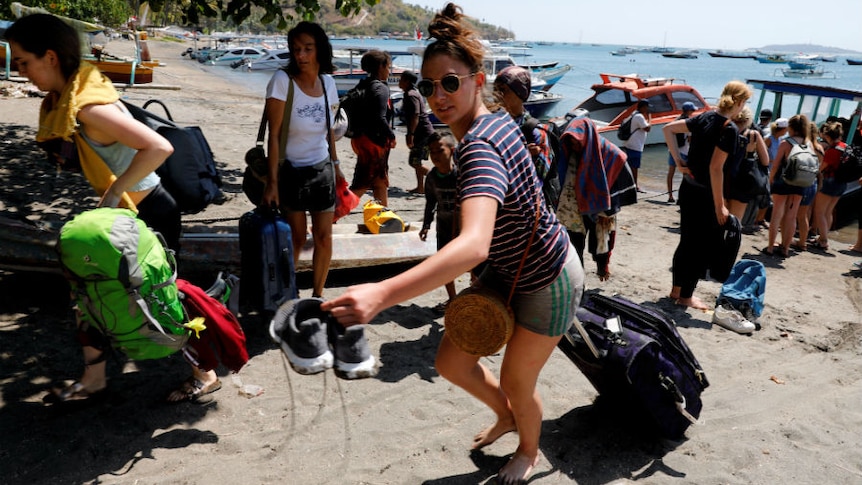 Foreign tourists carry their belongings on the beach