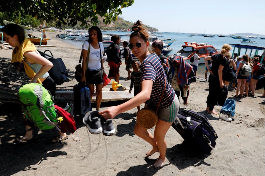 Foreign tourists carry their belongings on the beach