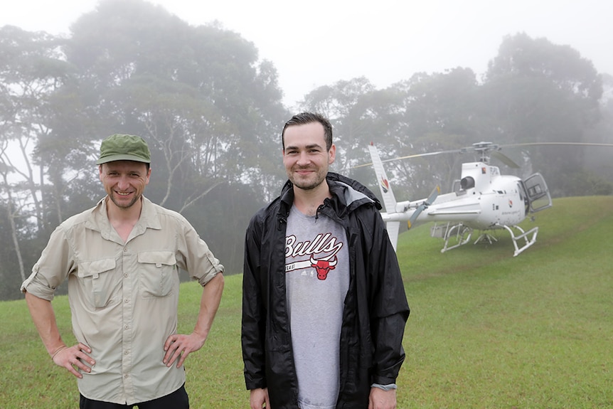 Luke Gibbs and Matt Holbrook standing in mist in front of helicopter.
