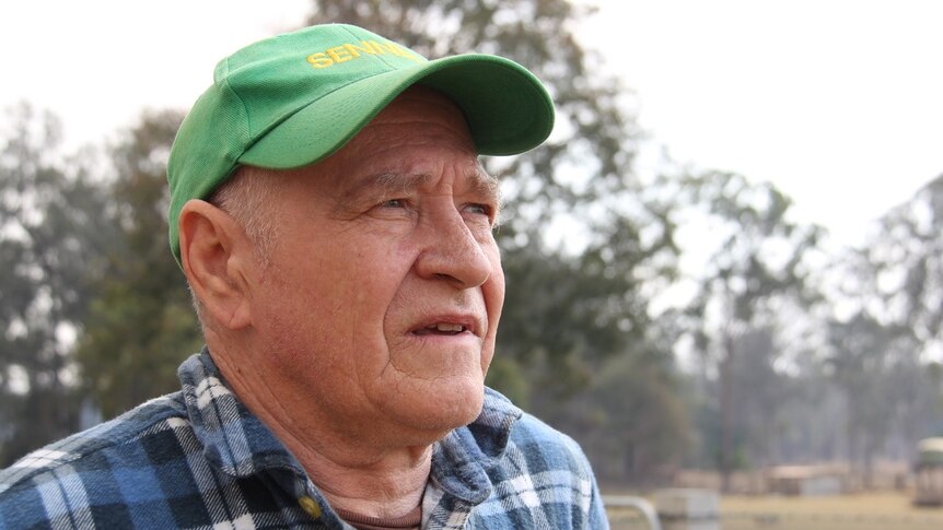 A man in a green hap in front of a property.