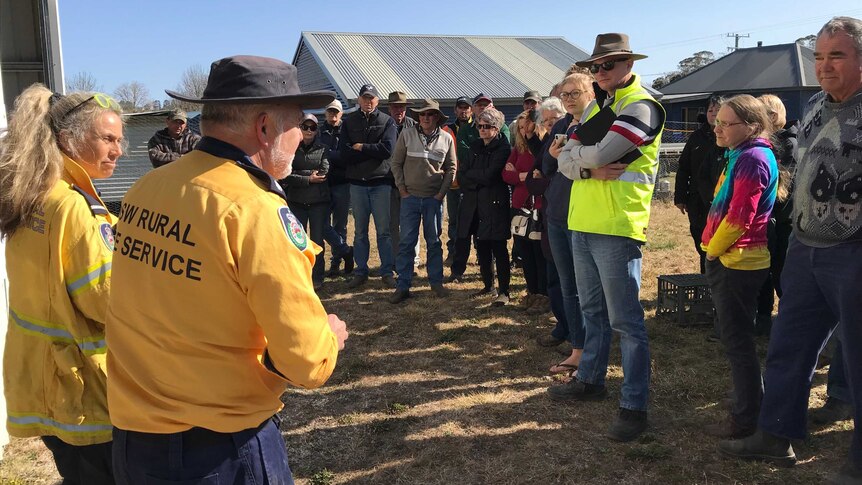 A number of people listening to a rural fire service worker.