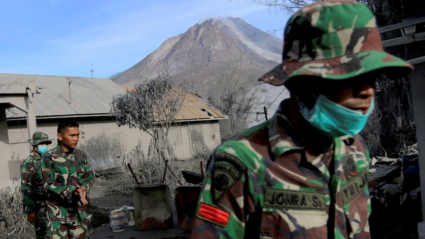 A soldier helps others search an area following a deadly eruption of Mount Sinabung volcano in Gamber Village, Indonesia.