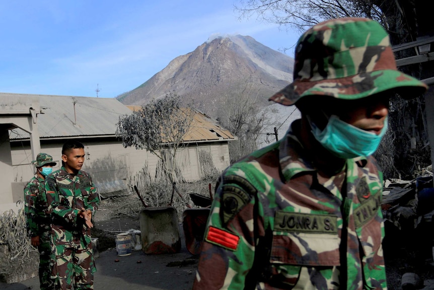 A soldier helps others search an area following a deadly eruption of Mount Sinabung volcano in Gamber Village, Indonesia.