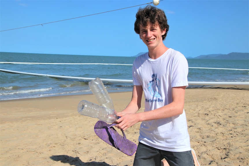 Arlian Ecker on the beach holding some plastic bottles