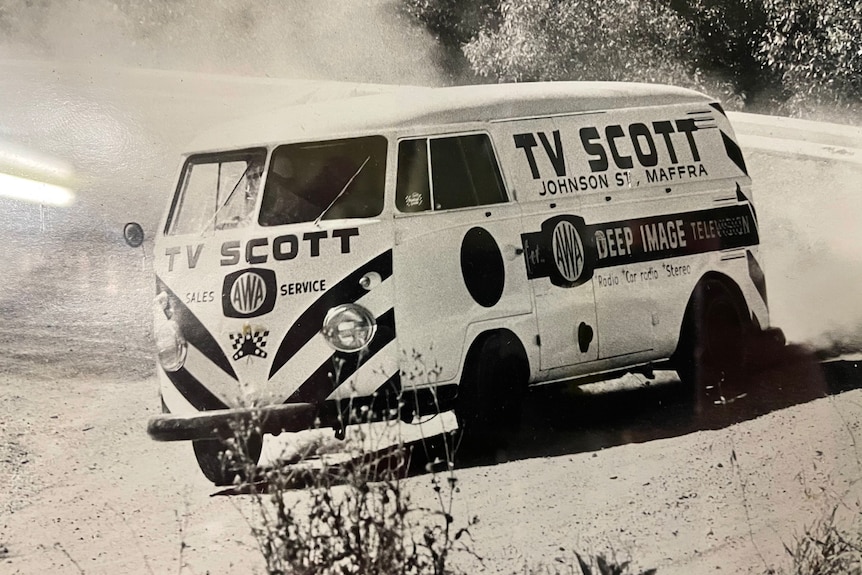 A black and white photograph of a Kombi van with TV Scott branding
