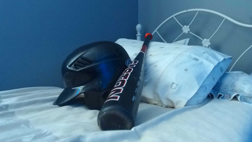Baseball bat and helmet on bed.