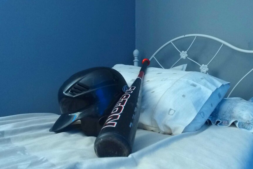 Baseball bat and helmet on bed.