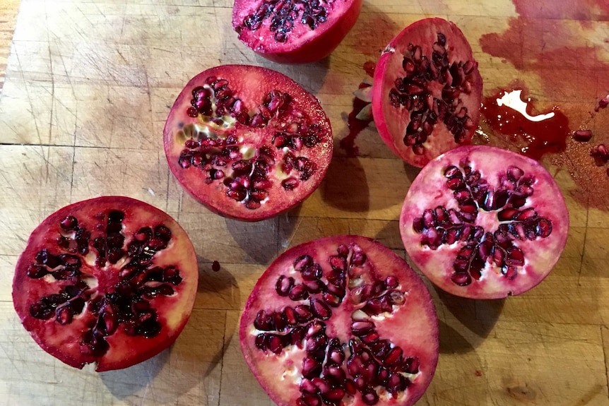 Pomegranate halves sitting on a board.