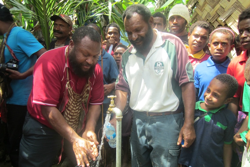 Community members gather around a running tap.