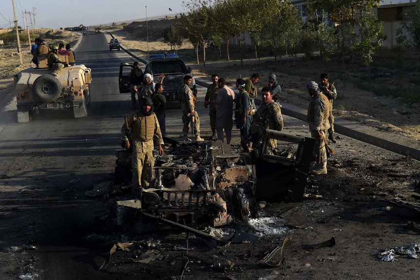 Afghan security forces investigate a site where vehicles were burned
