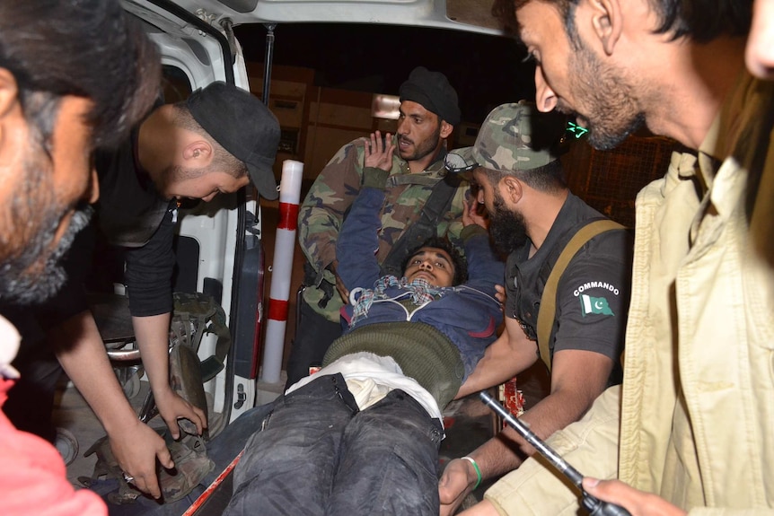 Pakistani volunteers and police officers rush an injured person to a hospital in Quetta, Pakistan, Monday, Oct. 24, 2016.