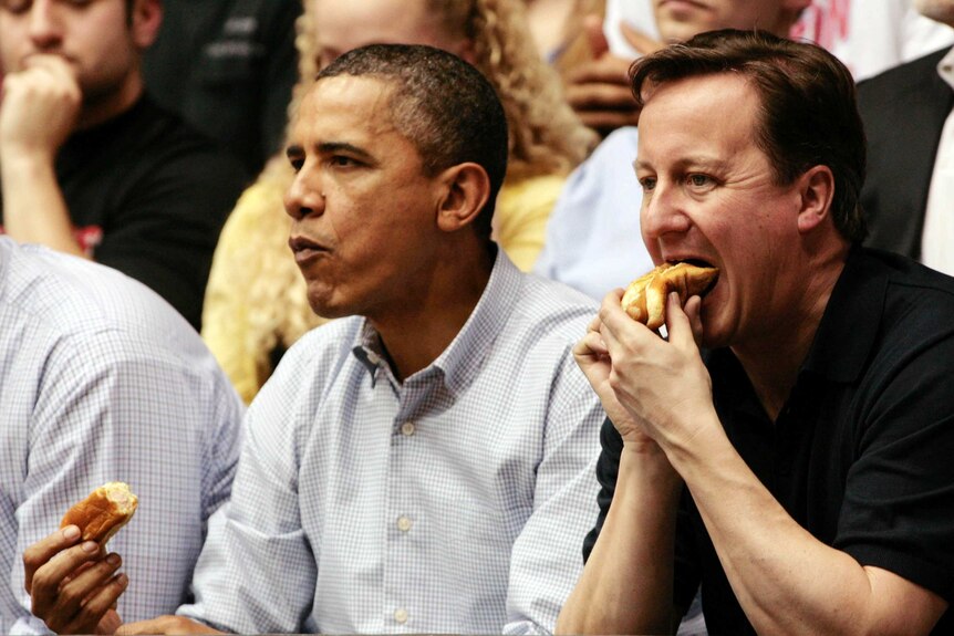 Mr Obama and Mr Cameron eat hot dogs at a basketball tournament