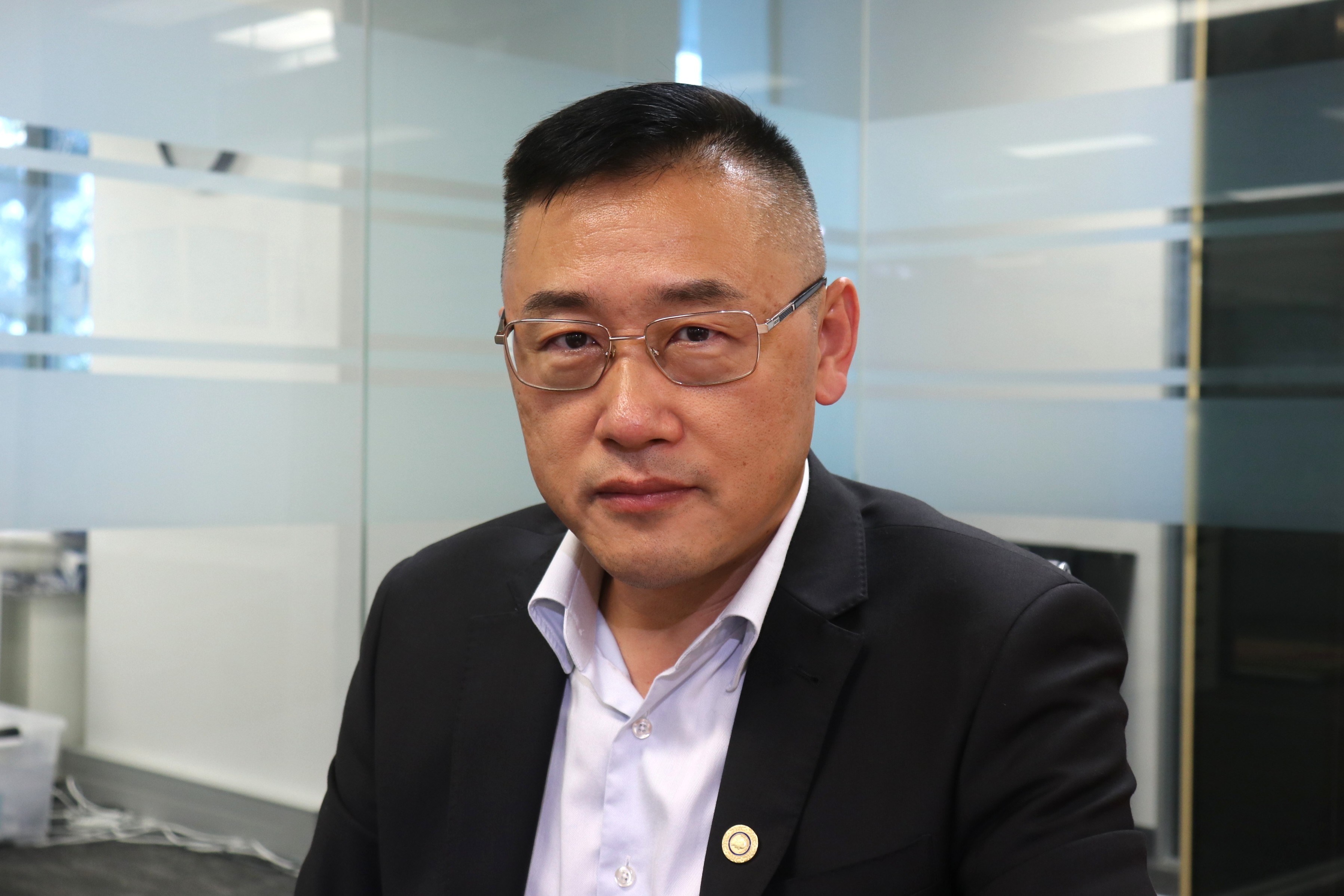 Middle aged man in a suit with glasses looking serious