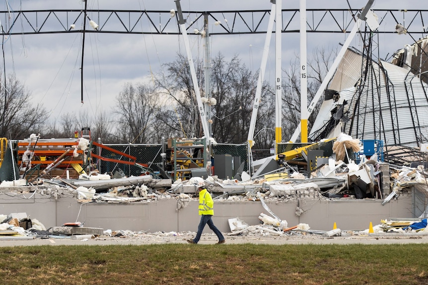 An emergency worker walks past wreckage at the Amazon distribution centre