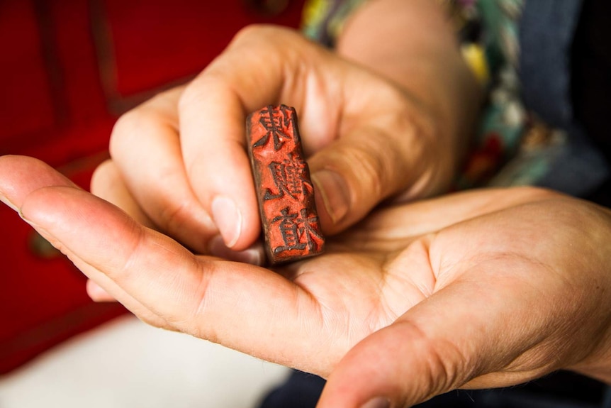 Close-up of woman's hands holding a traditional Chinese signature stamp