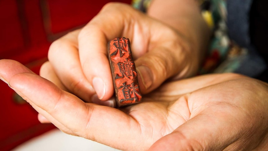 Close-up of woman's hands holding a traditional Chinese signature stamp