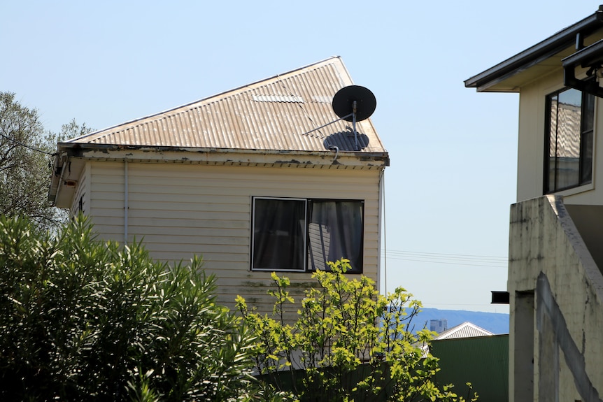 An outside view of the Cringila half house, showing half a room and cream weatherboard exterior.