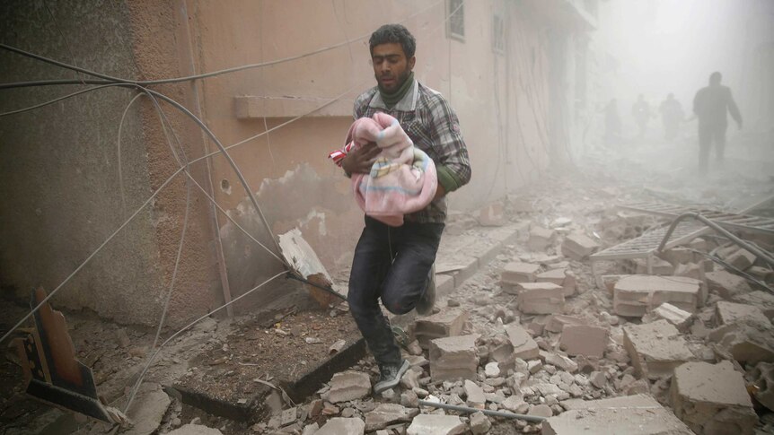 Man carries baby through Syrian rubble