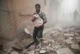 Man carries baby through Syrian rubble